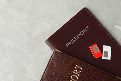 Photo of Passports and SIM cards on grey marble table, flat lay. Space for text