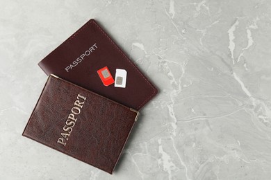 Photo of Passports and SIM cards on grey marble table, flat lay. Space for text