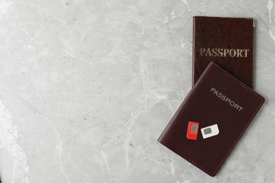 Passports and SIM cards on grey marble table, flat lay. Space for text