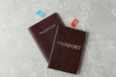 Passports and SIM cards on grey marble table, flat lay