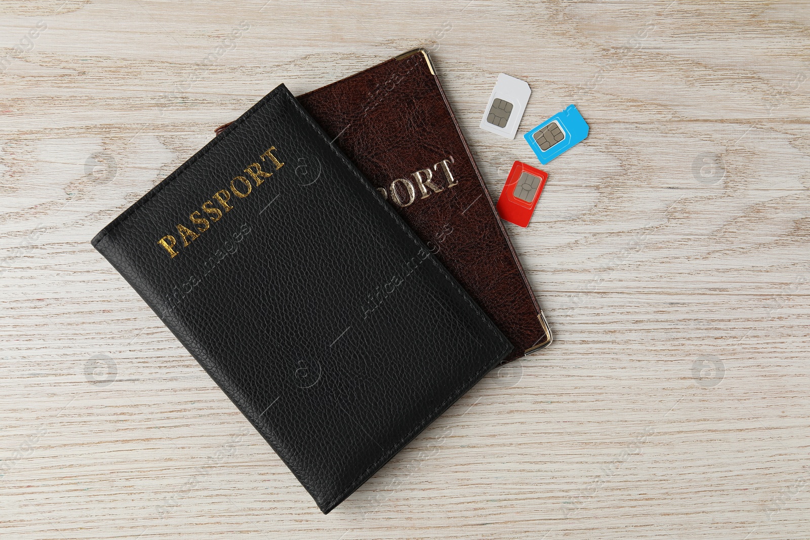 Photo of Passports and SIM cards on wooden table, flat lay