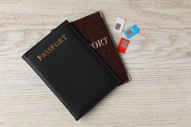 Passports and SIM cards on wooden table, flat lay