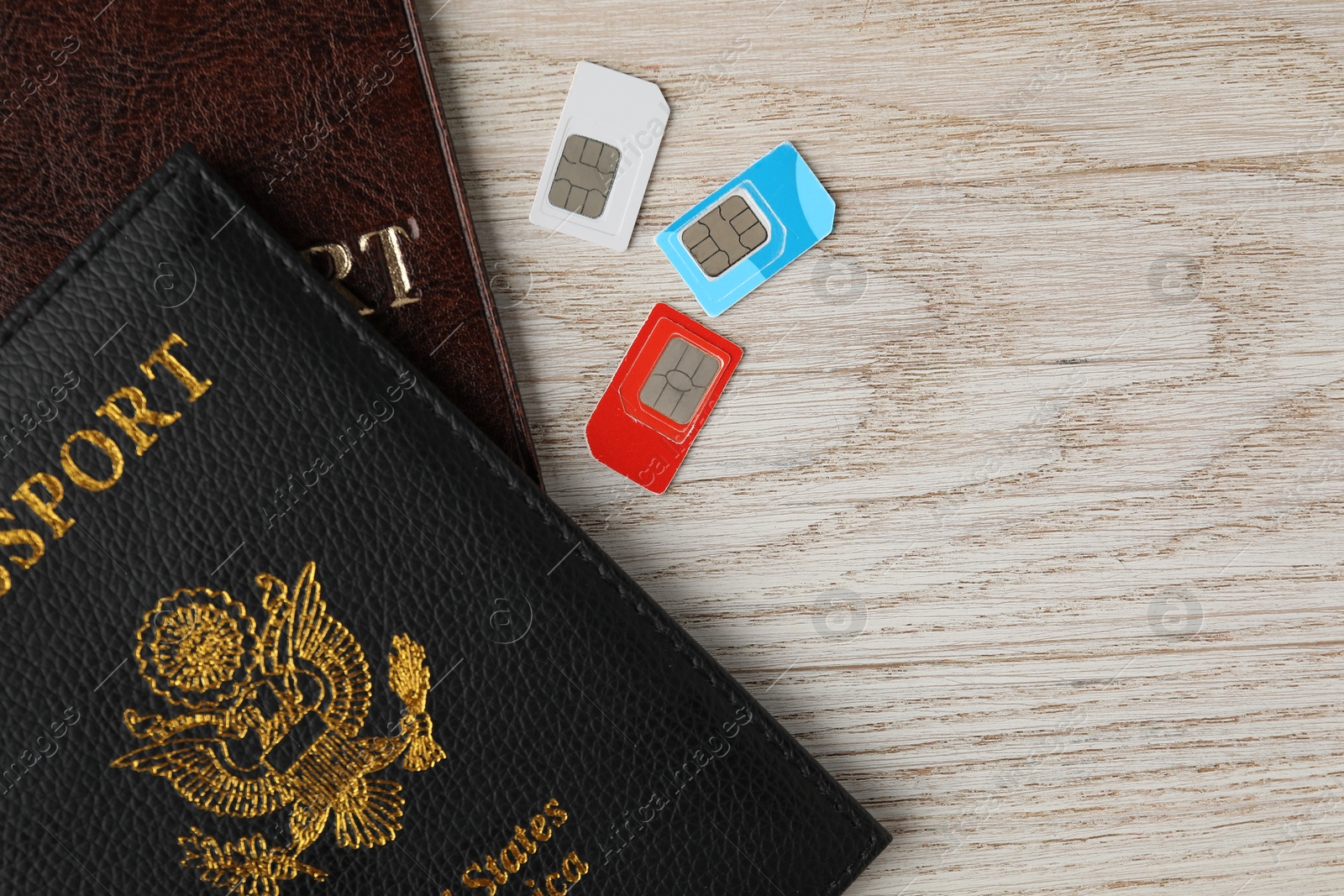 Photo of Passports and SIM cards on wooden table, flat lay