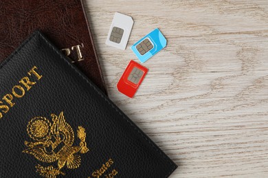 Passports and SIM cards on wooden table, flat lay