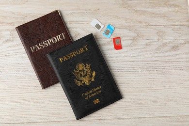 Passports and SIM cards on wooden table, flat lay