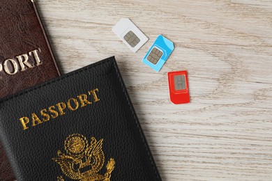 Photo of Passports and SIM cards on wooden table, flat lay