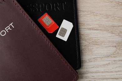 Photo of Passports and SIM cards on wooden table, flat lay