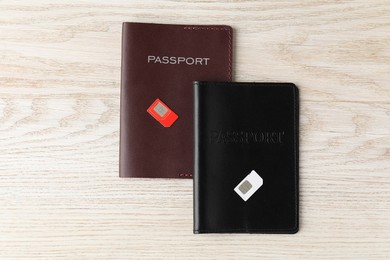 Passports and SIM cards on wooden table, flat lay