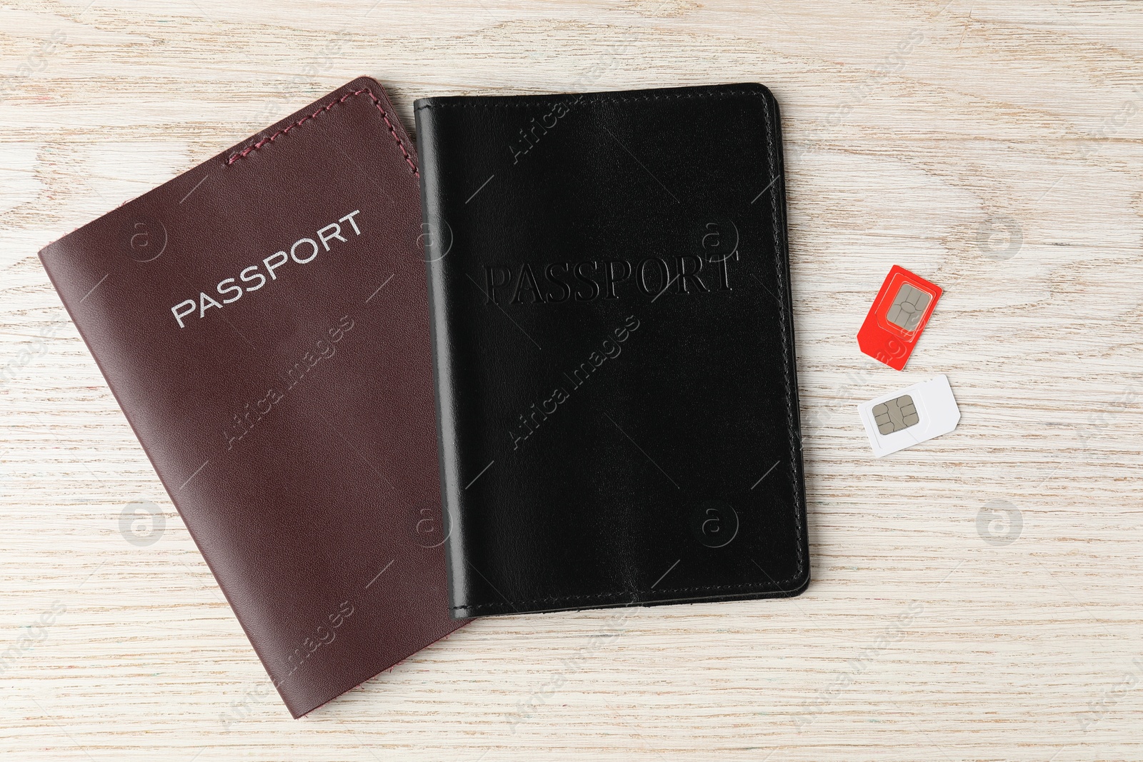 Photo of Passports and SIM cards on wooden table, flat lay