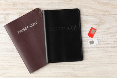 Photo of Passports and SIM cards on wooden table, flat lay