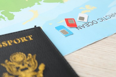 Photo of Passport, SIM cards and world map on wooden table, closeup