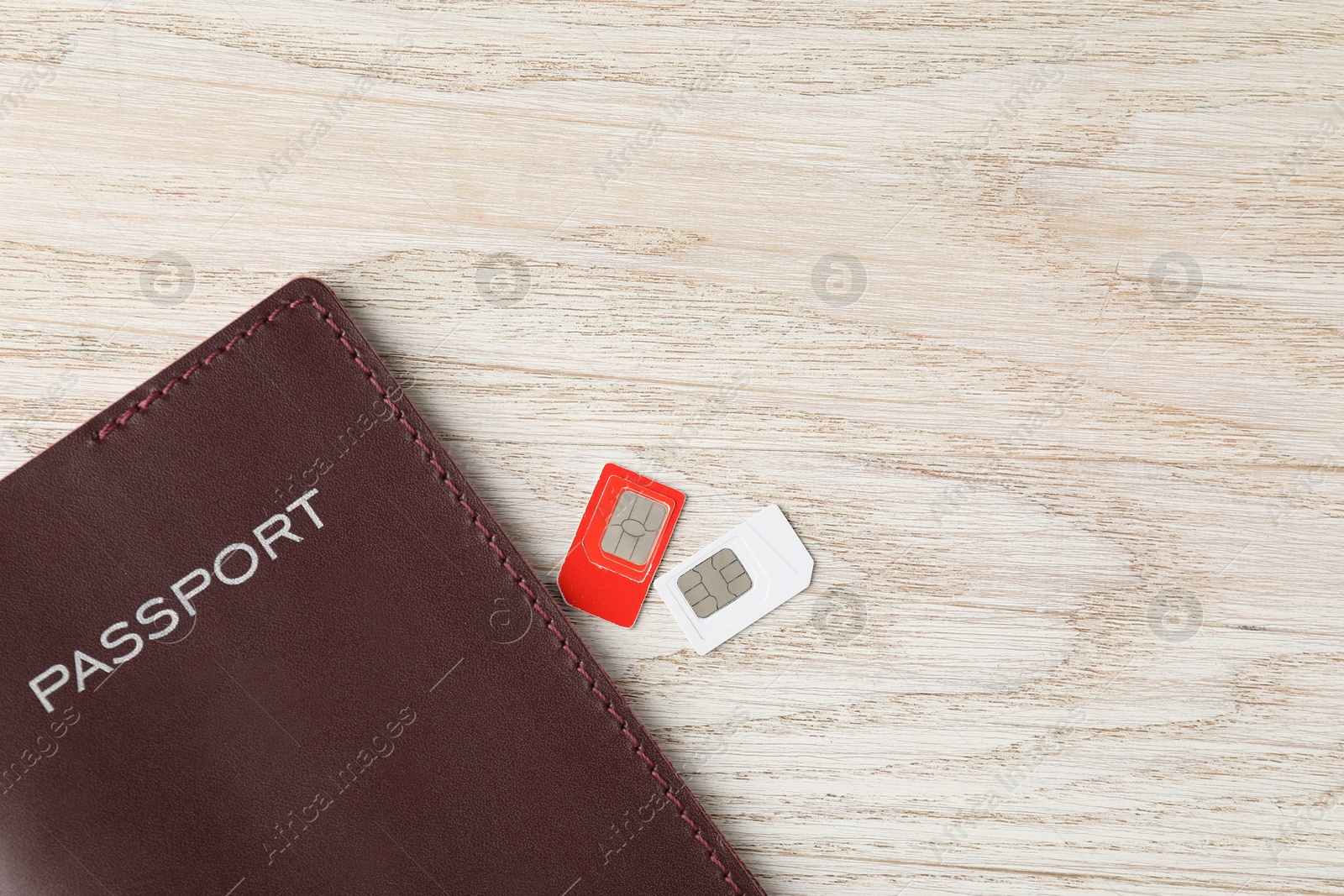 Photo of Passport and SIM cards on wooden table, flat lay. Space for text