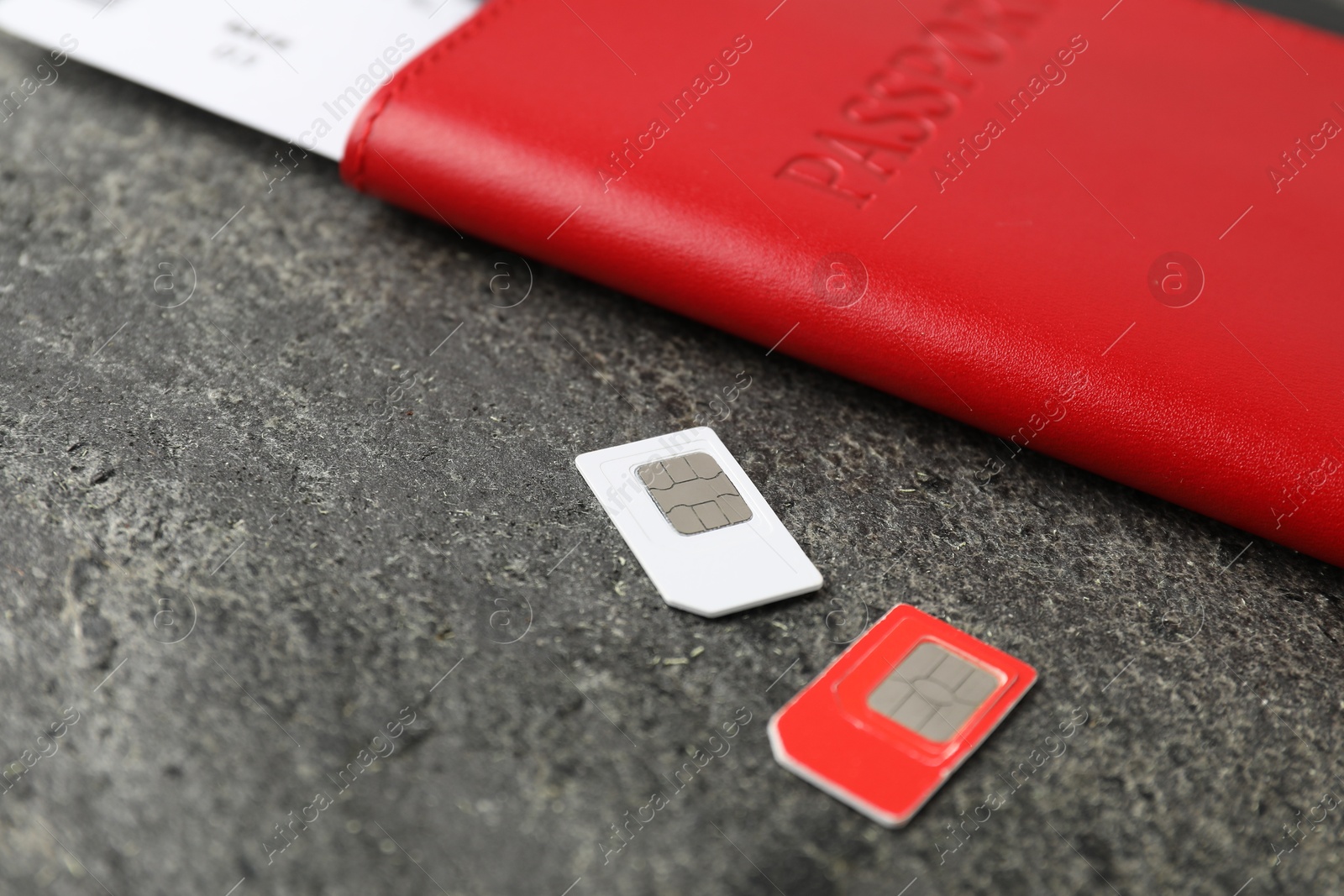 Photo of Passport and SIM cards on grey textured table, closeup