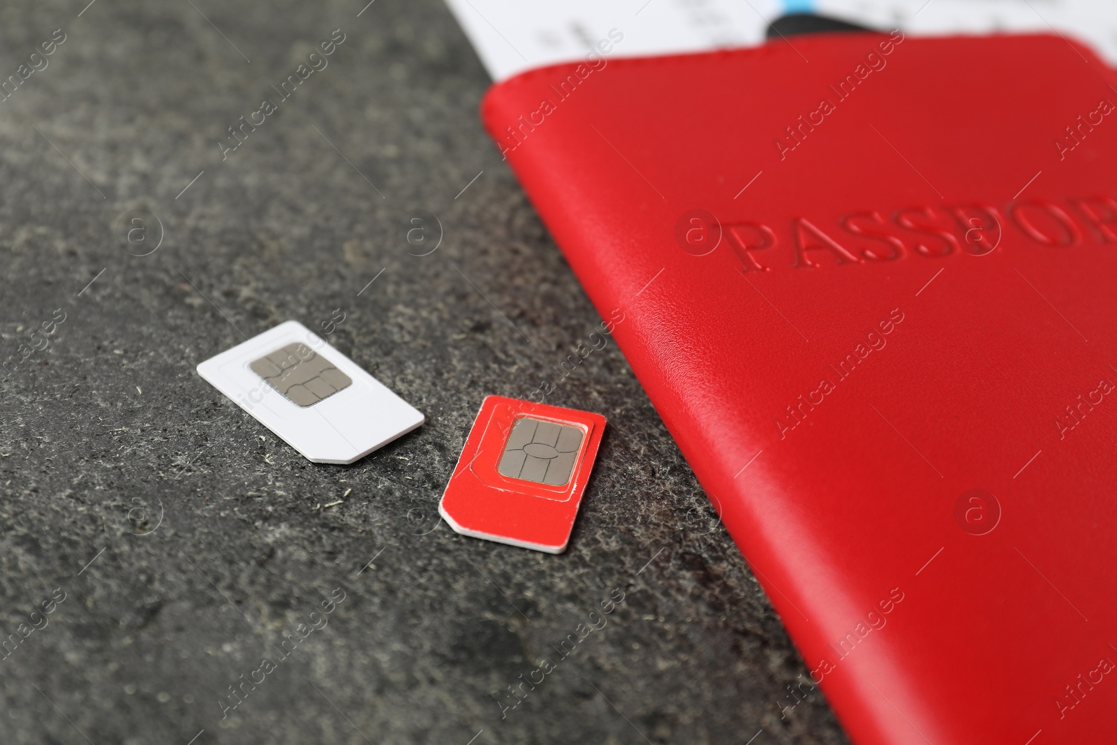 Photo of Passport and SIM cards on grey textured table, closeup