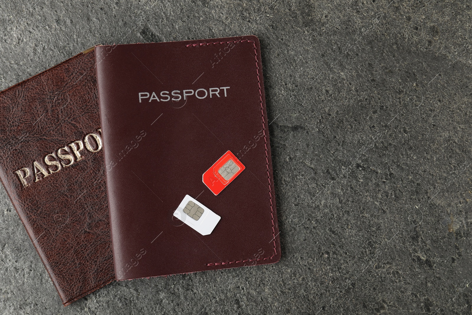 Photo of Passports and SIM cards on grey textured table, flat lay. Space for text