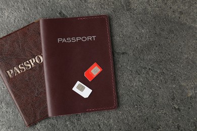 Passports and SIM cards on grey textured table, flat lay. Space for text