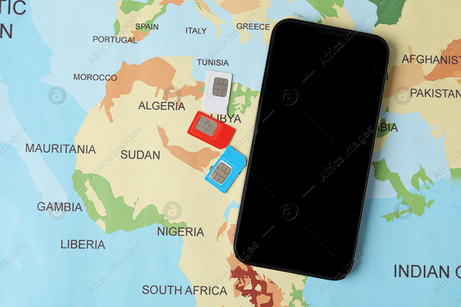 Photo of SIM cards and smartphone on world map, flat lay