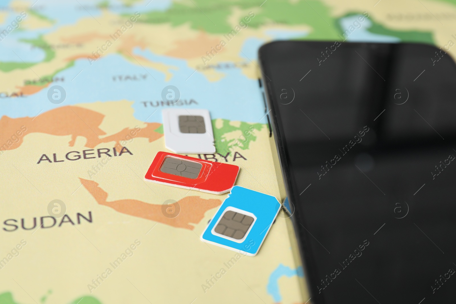 Photo of SIM cards and smartphone on world map, closeup