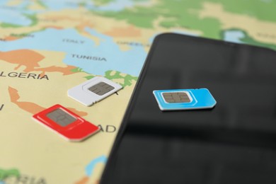 SIM cards and smartphone on world map, closeup