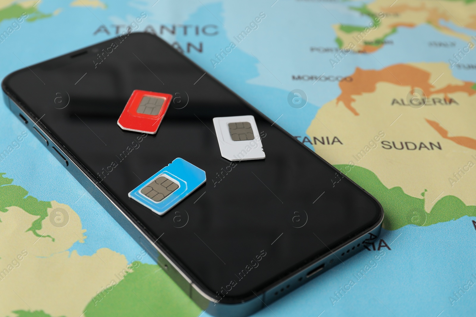 Photo of SIM cards and smartphone on world map, closeup