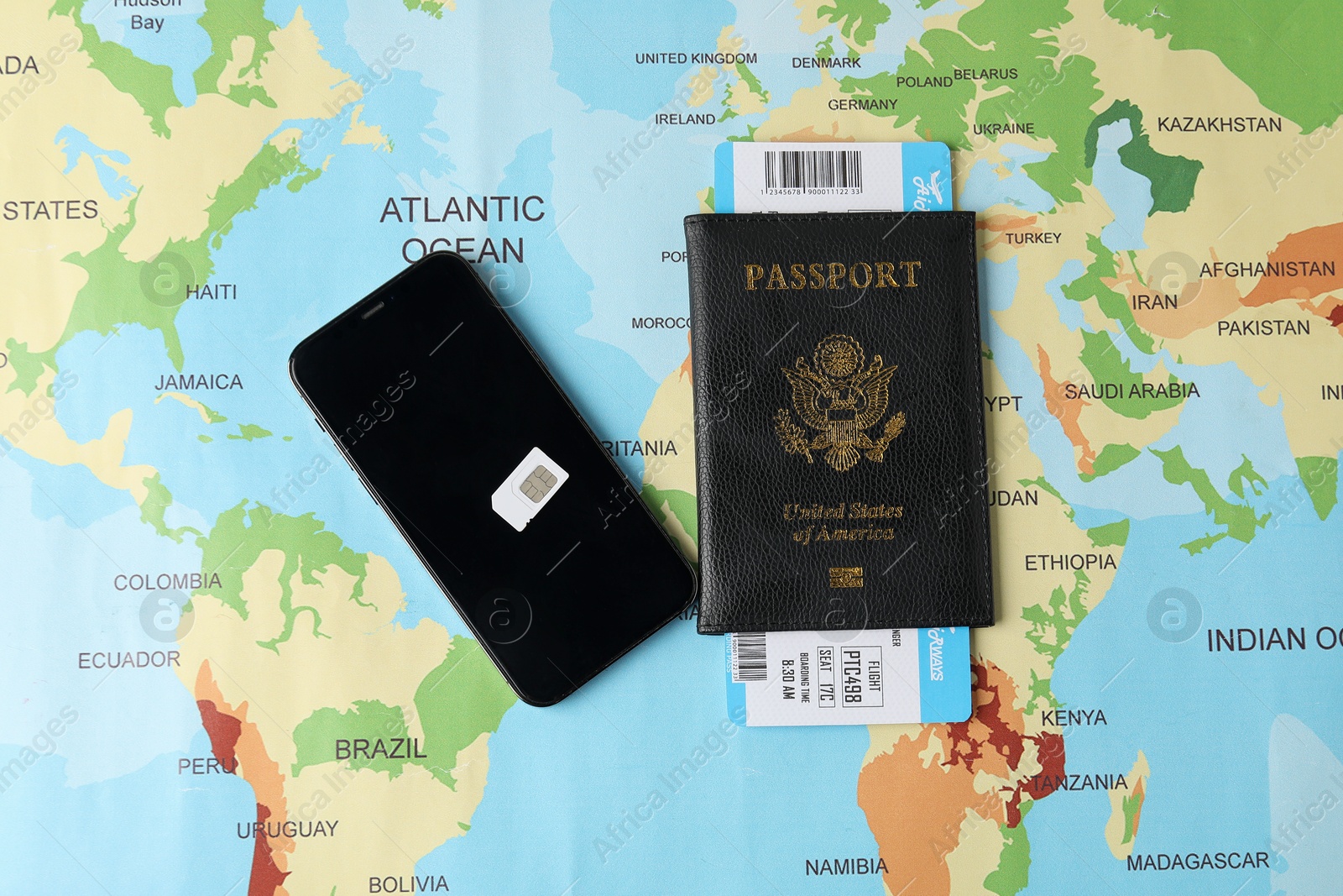 Photo of SIM card, smartphone and passport with ticket on world map, flat lay