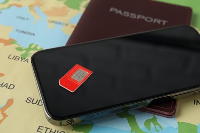 SIM card, smartphone and passport on world map, closeup