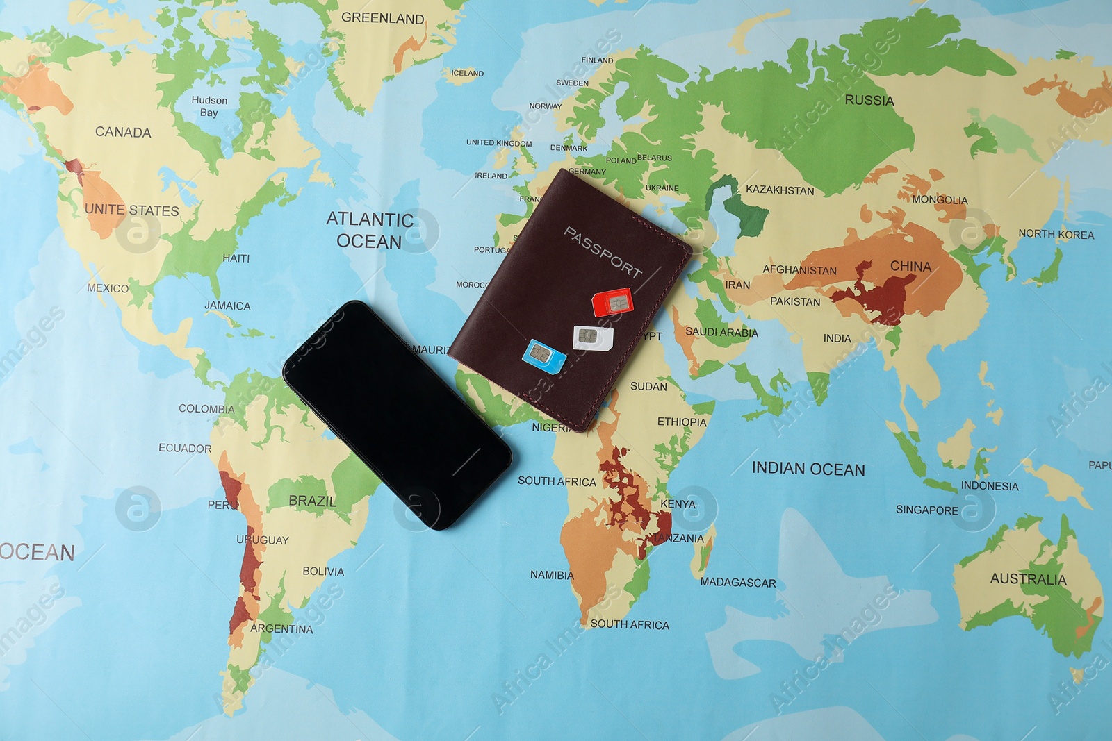 Photo of SIM cards, smartphone and passport on world map, flat lay