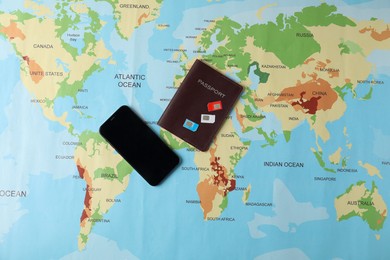 SIM cards, smartphone and passport on world map, flat lay