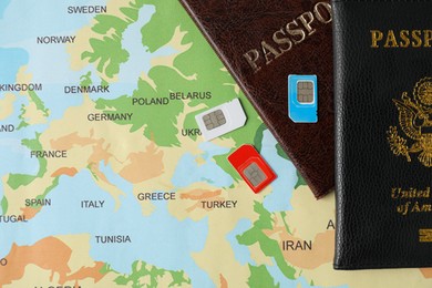 SIM cards and passports on world map, flat lay