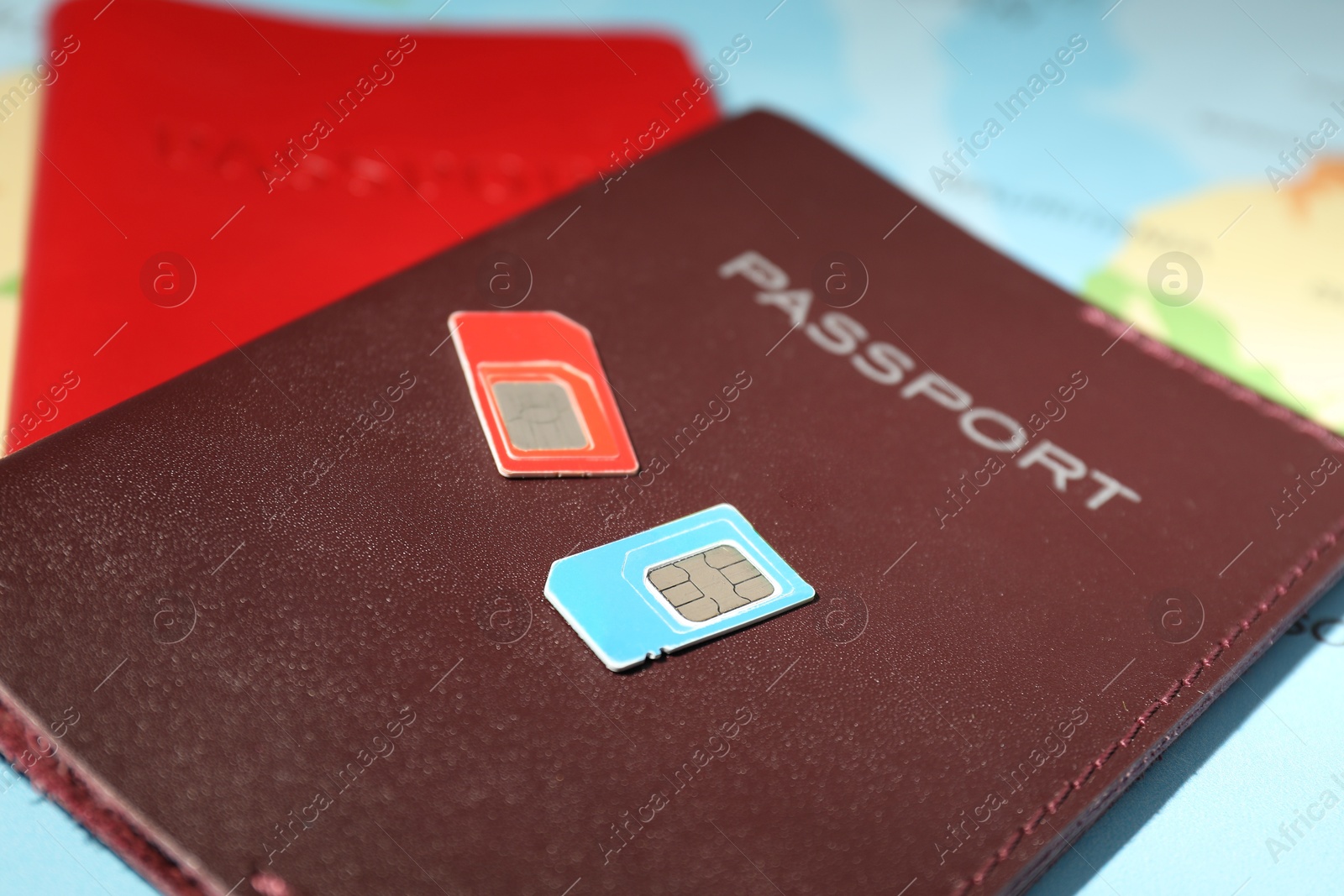 Photo of Modern SIM cards and passports on world map, closeup