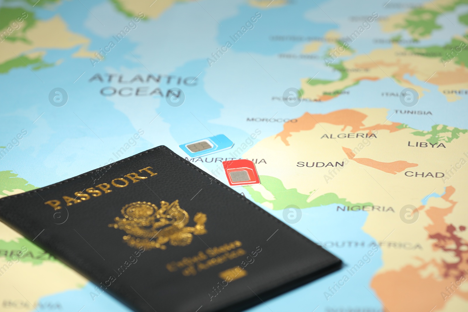 Photo of Modern SIM cards and passport on world map, closeup