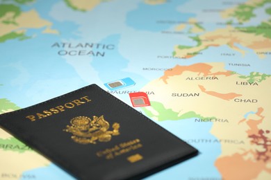 Photo of Modern SIM cards and passport on world map, closeup