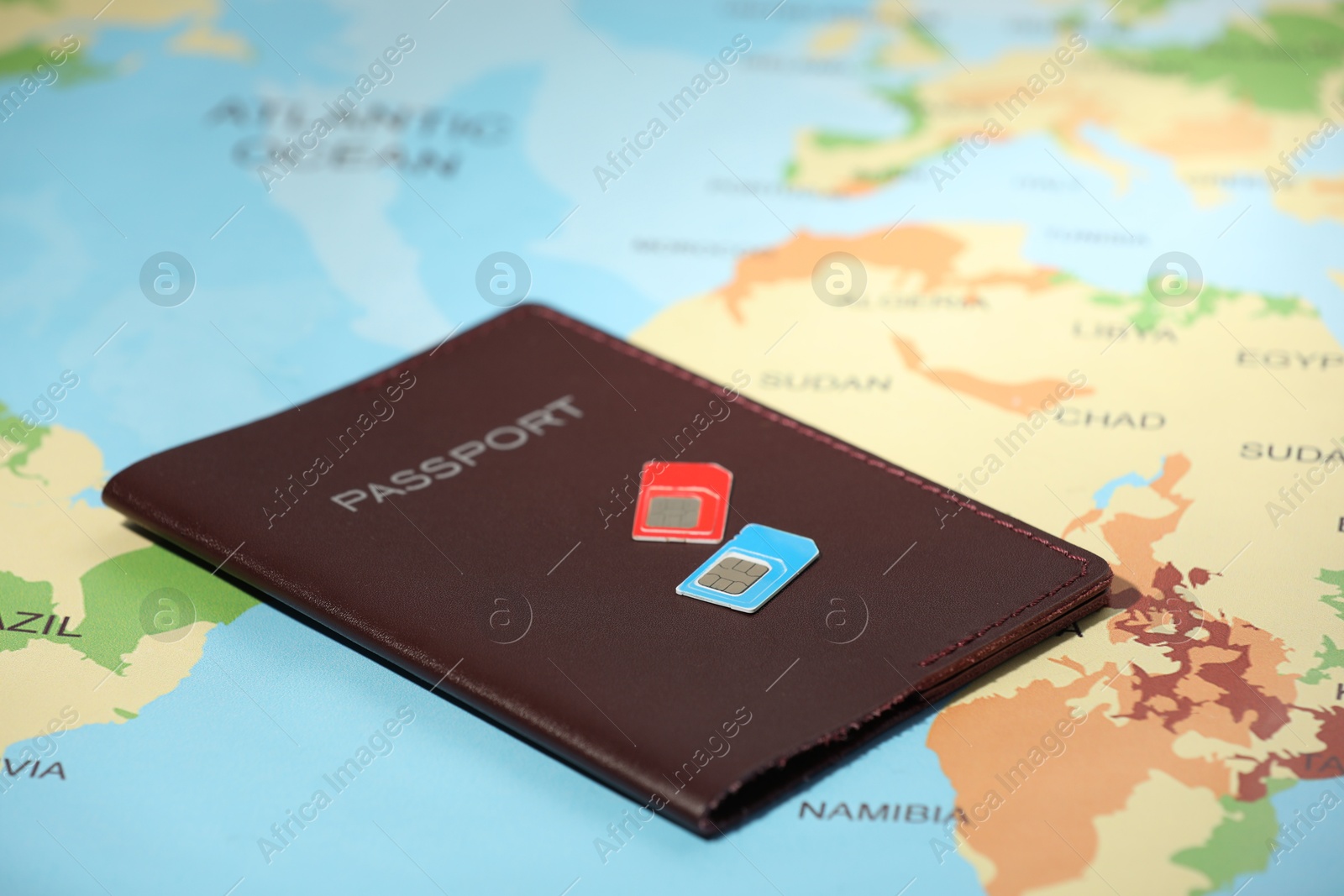 Photo of Modern SIM cards and passport on world map, closeup