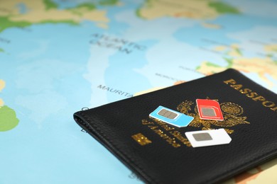 Modern SIM cards and passport on world map, closeup