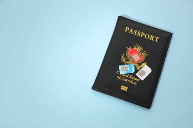 Modern SIM cards and passport on light blue background, top view. Space for text