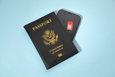 Photo of Modern SIM card, smartphone and passport on light blue background, top view