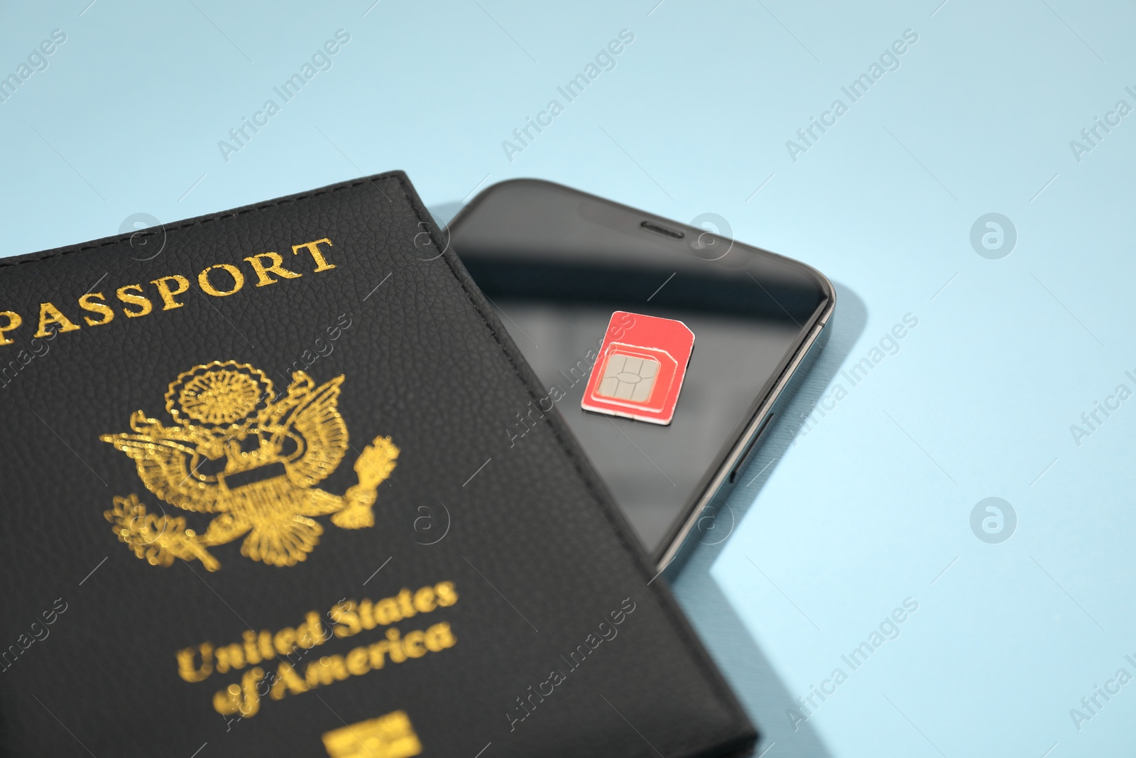 Photo of Modern SIM card, smartphone and passport on light blue background, closeup