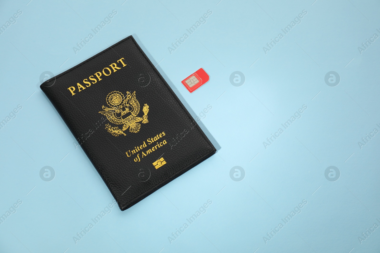 Photo of Modern SIM card and passport on light blue background