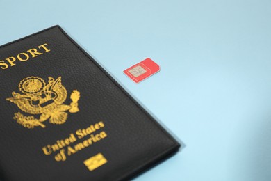 Photo of Modern SIM card and passport on light blue background, closeup