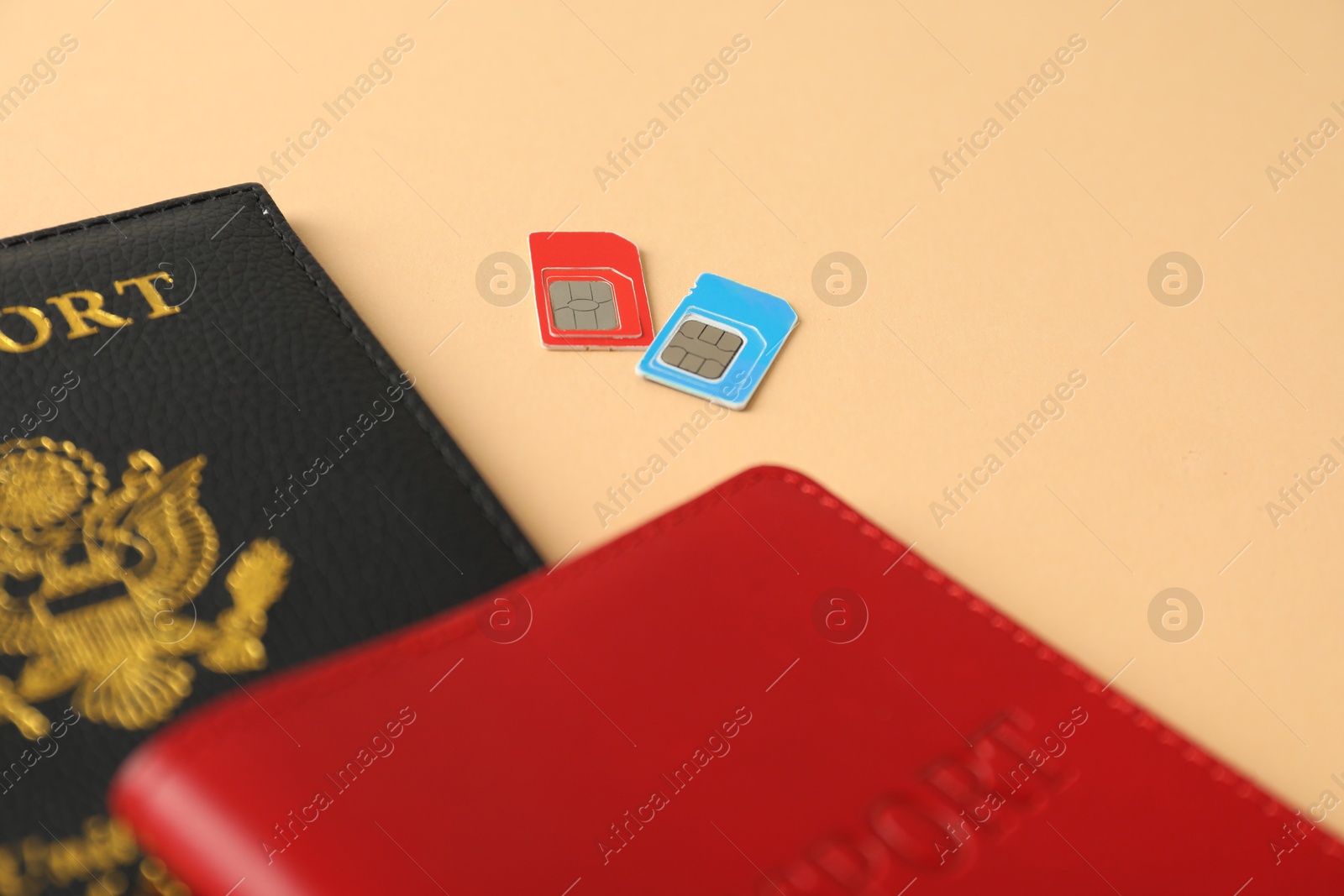 Photo of Modern SIM cards and passport on beige background, closeup