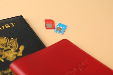 Modern SIM cards and passport on beige background, closeup