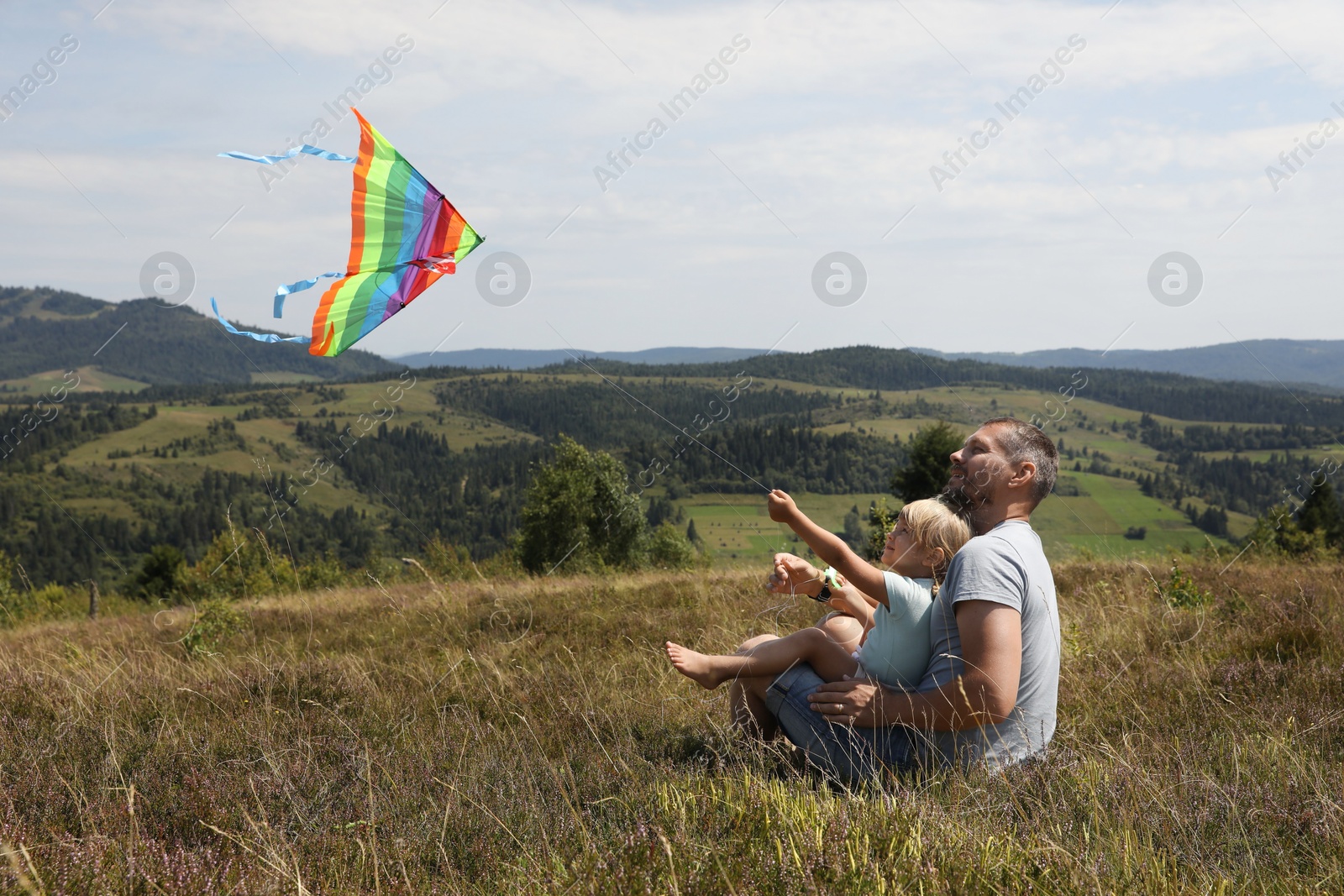 Photo of Father with daughter flying kite at field