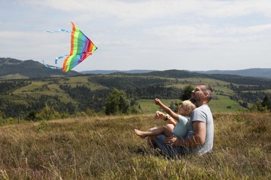 Photo of Father with daughter flying kite at field