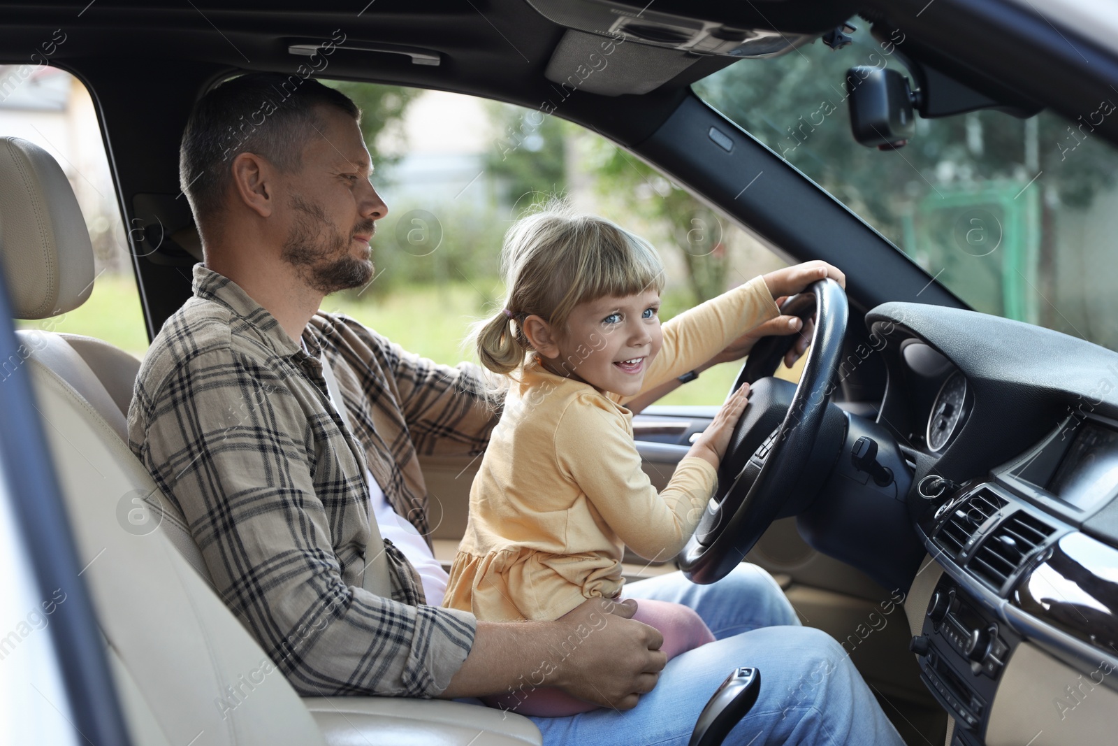 Photo of Man with daughter holding steering wheel inside car