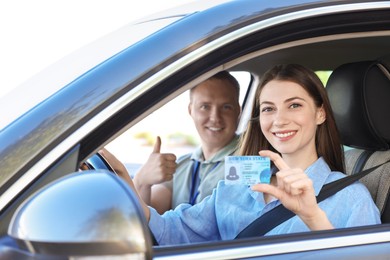 Driving school. Woman showing driving licence after exam in car