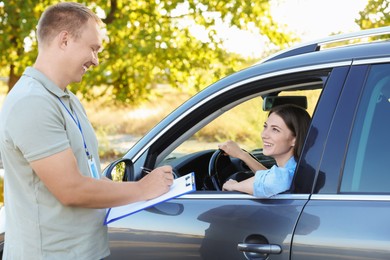 Photo of Examiner near car with student during test at driving school