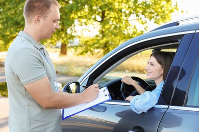 Examiner near car with student during test at driving school