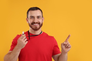 Photo of Happy young man with whistle on orange background