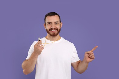 Photo of Happy young man with whistle on purple background