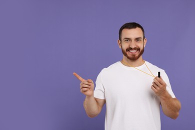 Happy young man with whistle on purple background, space for text